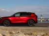 Side view of the 2026 Mazda CX-5 in red, elegantly parked at a scenic pier.