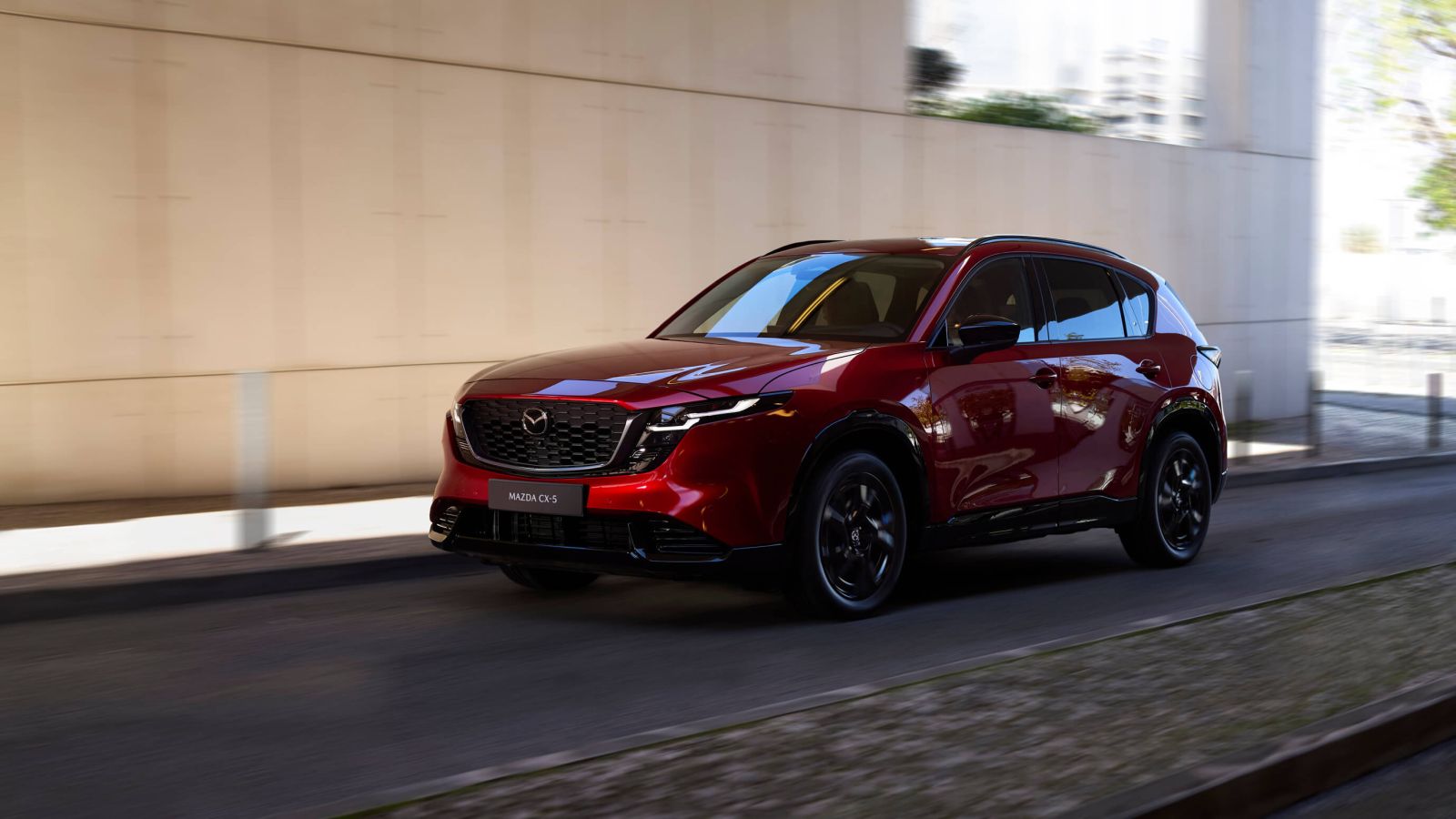 The 2026 Mazda CX-5 driving down a city street, shown from the driver-side angle.